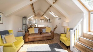 A loft-style living room with a brown leather sofa, yellow armchairs, and a wooden staircase. - Boutique Barn Secure Parking between York &Harrogate (York, North Yorkshire)