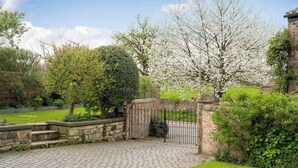 A paved driveway leading to a gated entrance with a stone wall and a metal gate. - Boutique Barn Secure Parking between York &Harrogate (York, North Yorkshire)