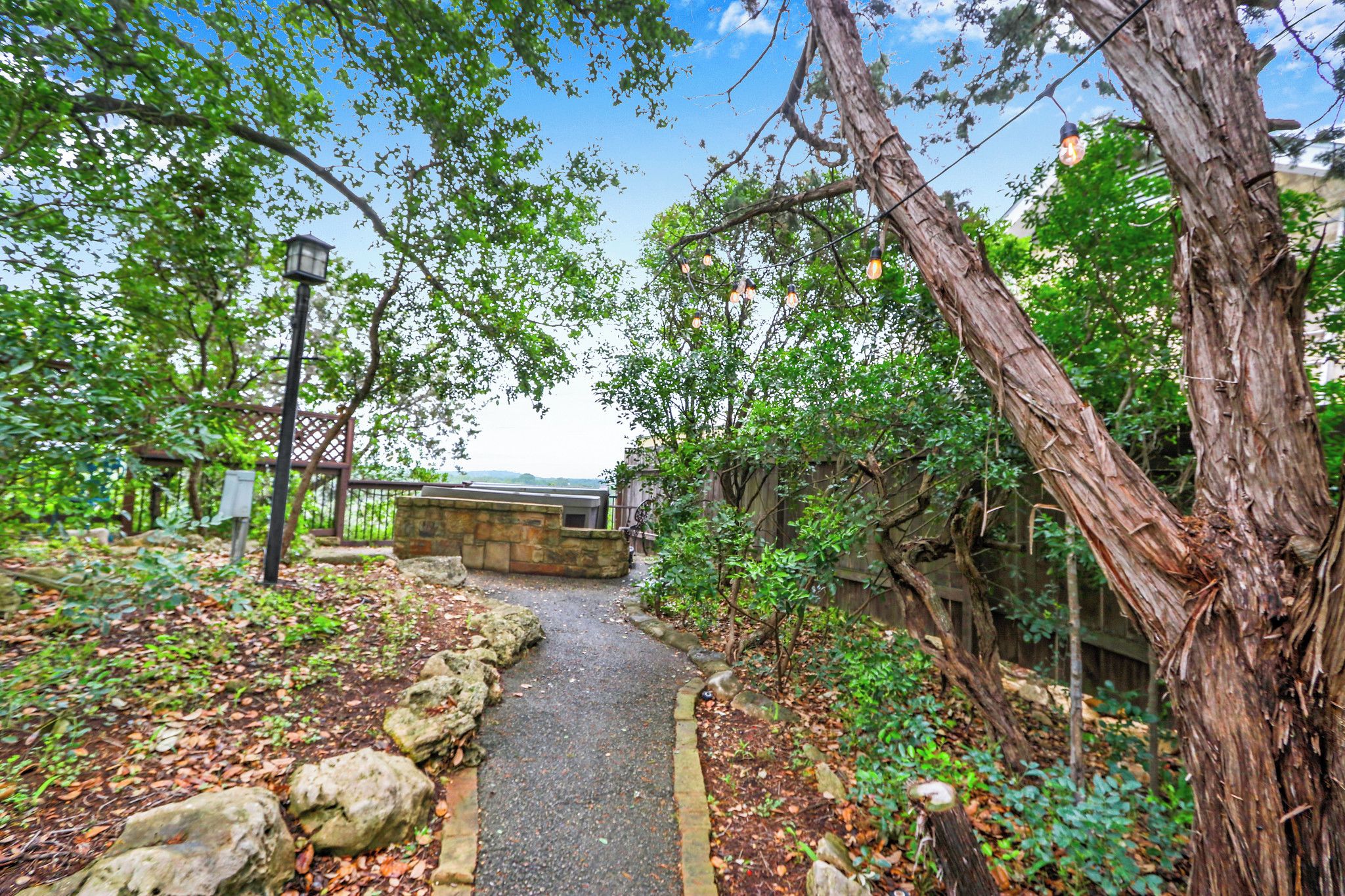 A pathway flanked by trees and a stone wall, leading to a building with a view.