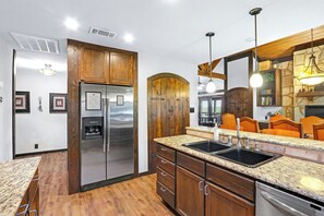 A kitchen with wooden cabinets, stainless steel appliances, and a granite countertop. - Clutter Falls Retreat with Two Homes, Hot Tubs & Guadalupe River Views (New Braunfels)