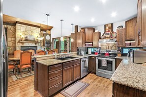 A modern kitchen with granite countertops, wooden cabinets, and stainless steel appliances. - Clutter Falls Retreat with Two Homes, Hot Tubs & Guadalupe River Views (New Braunfels)
