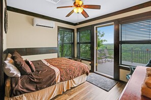 A bedroom with a large bed, a ceiling fan, and a view of the outdoors through a sliding glass door. - Clutter Falls Retreat with Two Homes, Hot Tubs & Guadalupe River Views (New Braunfels)