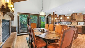 Uma sala de jantar espaçosa com uma grande mesa de madeira e cadeiras, lareira e vista para o exterior.