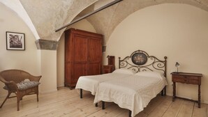 A bedroom with a bed, a chair, a wooden wardrobe, and a small table.