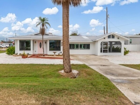 Une maison de plain-pied dotée d’une grande véranda à l’avant, d’un garage et d’une pelouse bien entretenue.