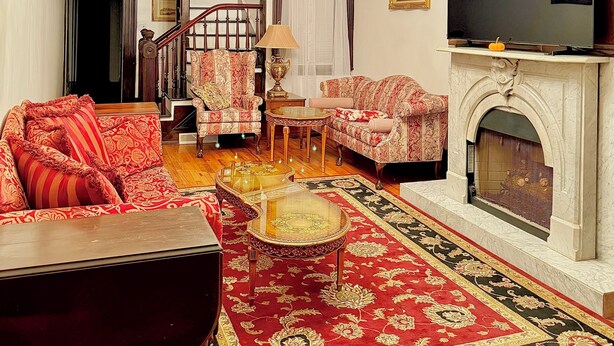 A traditional living room with a fireplace, a television, and a staircase leading to another level.