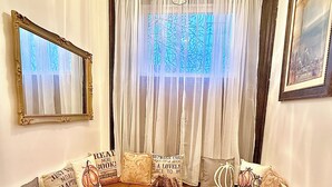 A cozy living room with a sectional sofa, a bench, and a large window with sheer curtains.