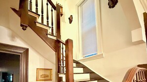 A wooden staircase with a handrail and a window with blinds.