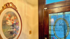 A door with a stained glass window and a framed floral painting on the wall.