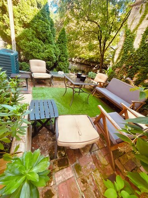 Un patio con mobiliario exterior, una mesa pequeña y una fuente de agua.