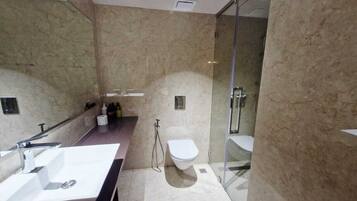 Un baño moderno con un lavabo blanco, inodoro y cabina de ducha con paredes de vidrio.