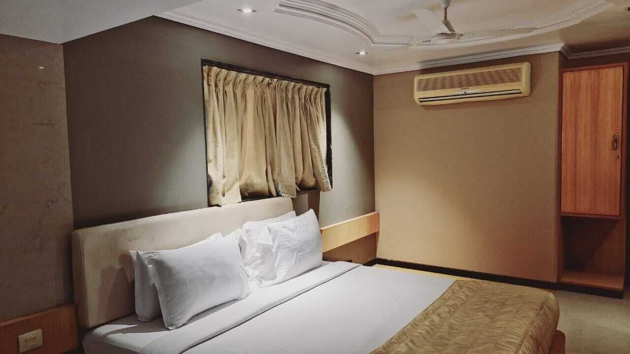 Ett hotellrum med en säng, en garderob och en luftkonditioneringsanläggning.