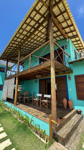 A two-story building with a wooden deck and a thatched roof. - Casa Pindorama com Vista Para o mar em Corumbau (Prado)