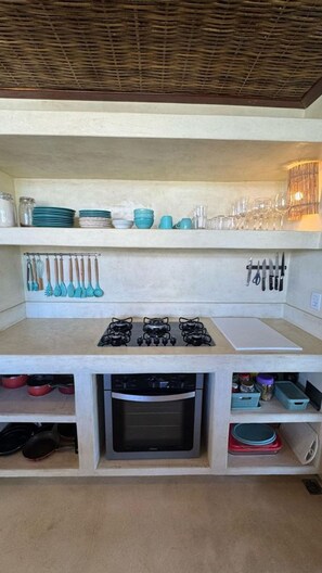 A kitchen with a gas stove, oven, and various utensils and cookware. - Casa Pindorama com Vista Para o mar em Corumbau (Prado)