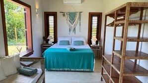 A bedroom with a bed, a wooden shelf, a woven rug, and a ceiling fan. - Casa Pindorama com Vista Para o mar em Corumbau (Prado)
