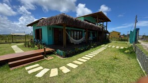 A house with a thatched roof, a hammock, and a paved pathway leading to the entrance. - Casa Pindorama com Vista Para o mar em Corumbau (Prado)