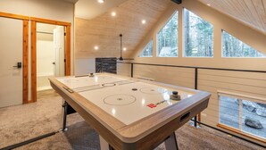 Een modern interieur met een houten plafond, grote ramen en een tafelvoetbalspel.