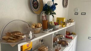 A buffet counter with various food items, including bread, pastries, and condiments.