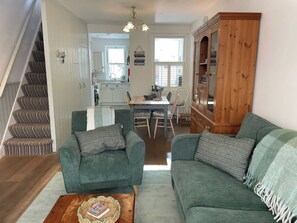 A living room with a sofa, a coffee table, and a staircase. - Seahorse Cottage (Weymouth)
