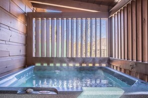 Ein Whirlpool mit einer Holzterrasse und Blick auf Bäume.