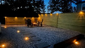 Um pátio externo com lareira, assentos e iluminação decorativa.