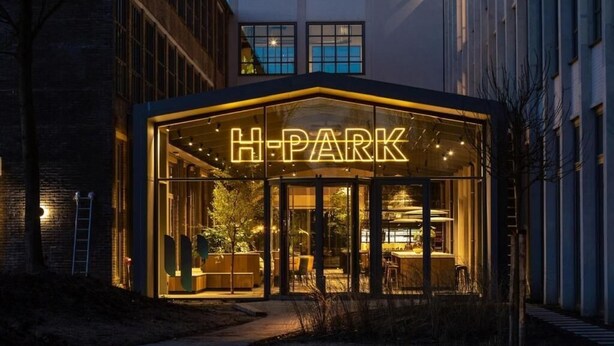 A modern building with a glass facade and the illuminated sign "H-PARK".