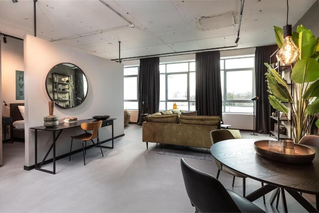 A modern living room with a round mirror, a sofa, a dining table, and a coffee table.