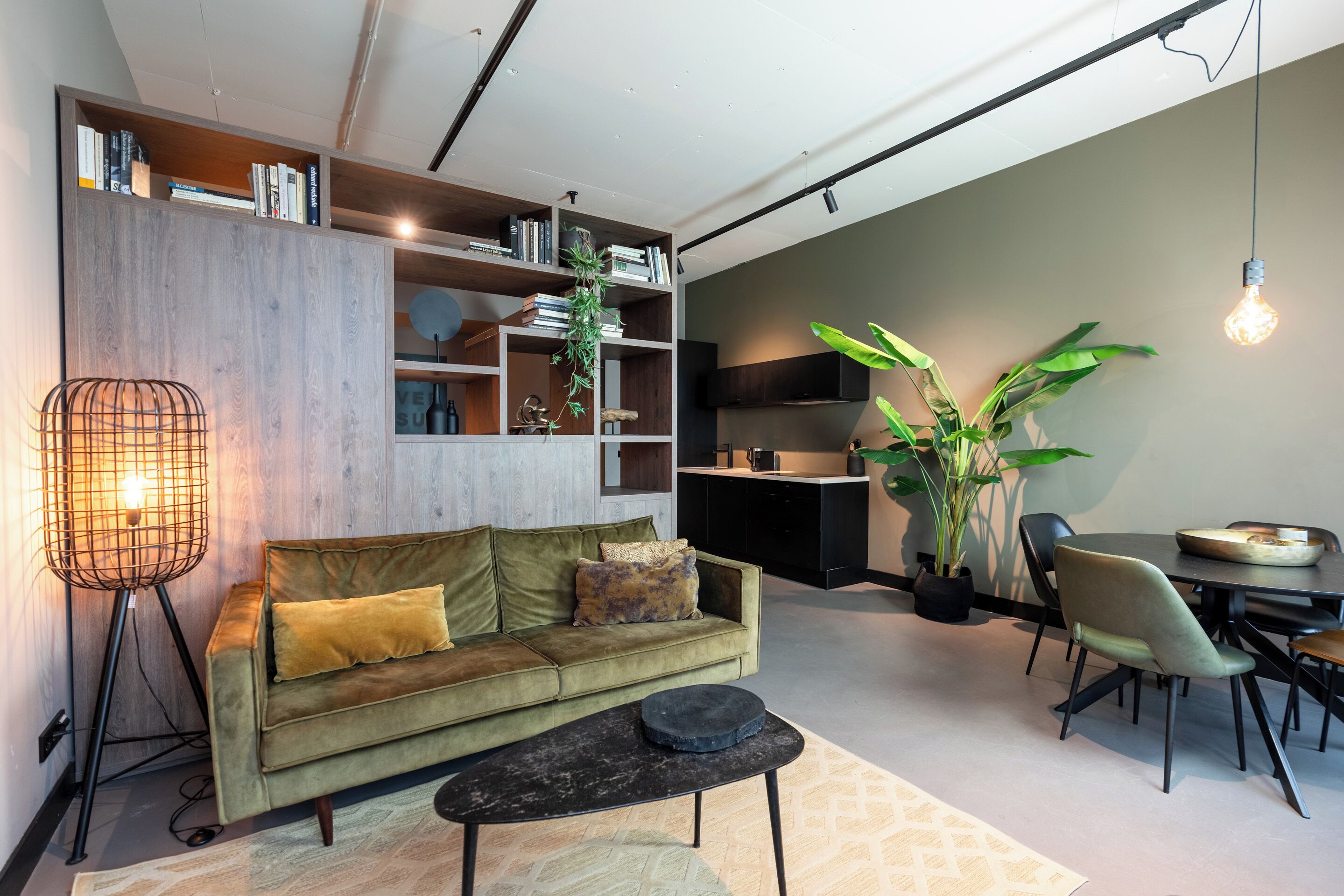 A modern living room with a sofa, coffee table, dining table, chairs, and a bookshelf.