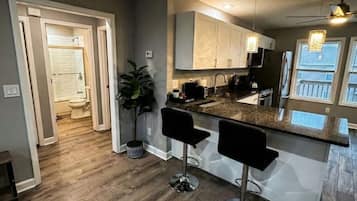 A modern kitchen with a wooden floor, two bar stools, and a built-in island.