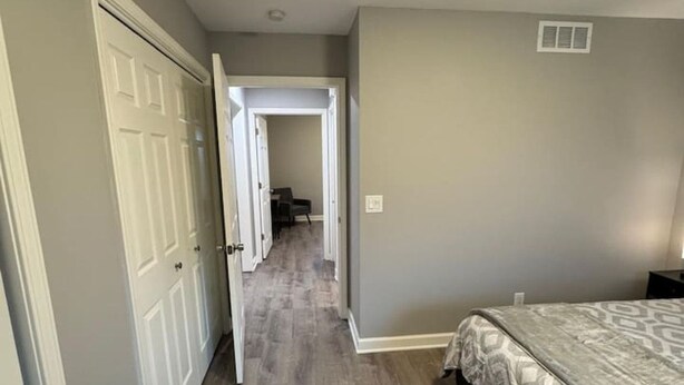 A bedroom with a bed, a door, and a hallway leading to another room. - Spacious 2BR Apt (Sleeps 6): 2 KING Beds & Balcony (South Beloit)
