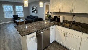 A modern kitchen with white cabinets, a stainless steel dishwasher, and a granite countertop. - Spacious 2BR Apt (Sleeps 6): 2 KING Beds & Balcony (South Beloit)