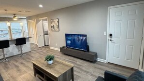 A modern living room with a flat-screen TV, a coffee table, and a sofa. - Spacious 2BR Apt (Sleeps 6): 2 KING Beds & Balcony (South Beloit)
