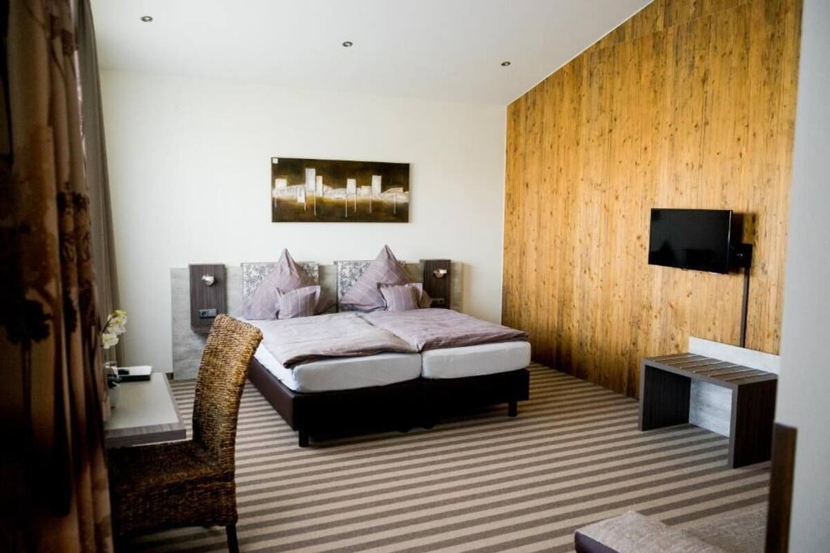 A hotel room with a large bed, a television, and a wooden accent wall.