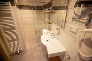 Une salle de bain avec une douche à parois de verre, un lavabo blanc et un miroir.