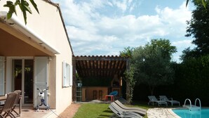 Ein Garten mit Swimmingpool, Sitzgelegenheiten im Freien und einer Grillanlage.