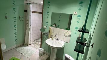 Une salle de bain avec un lavabo, un miroir et des murs verts.
