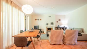 Una sala de estar con una mesa de comedor de madera, sillones a rayas, un sofá y una chimenea.