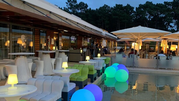 Un espace extérieur aménagé avec des tables et des chaises rondes, une piscine et des parasols.