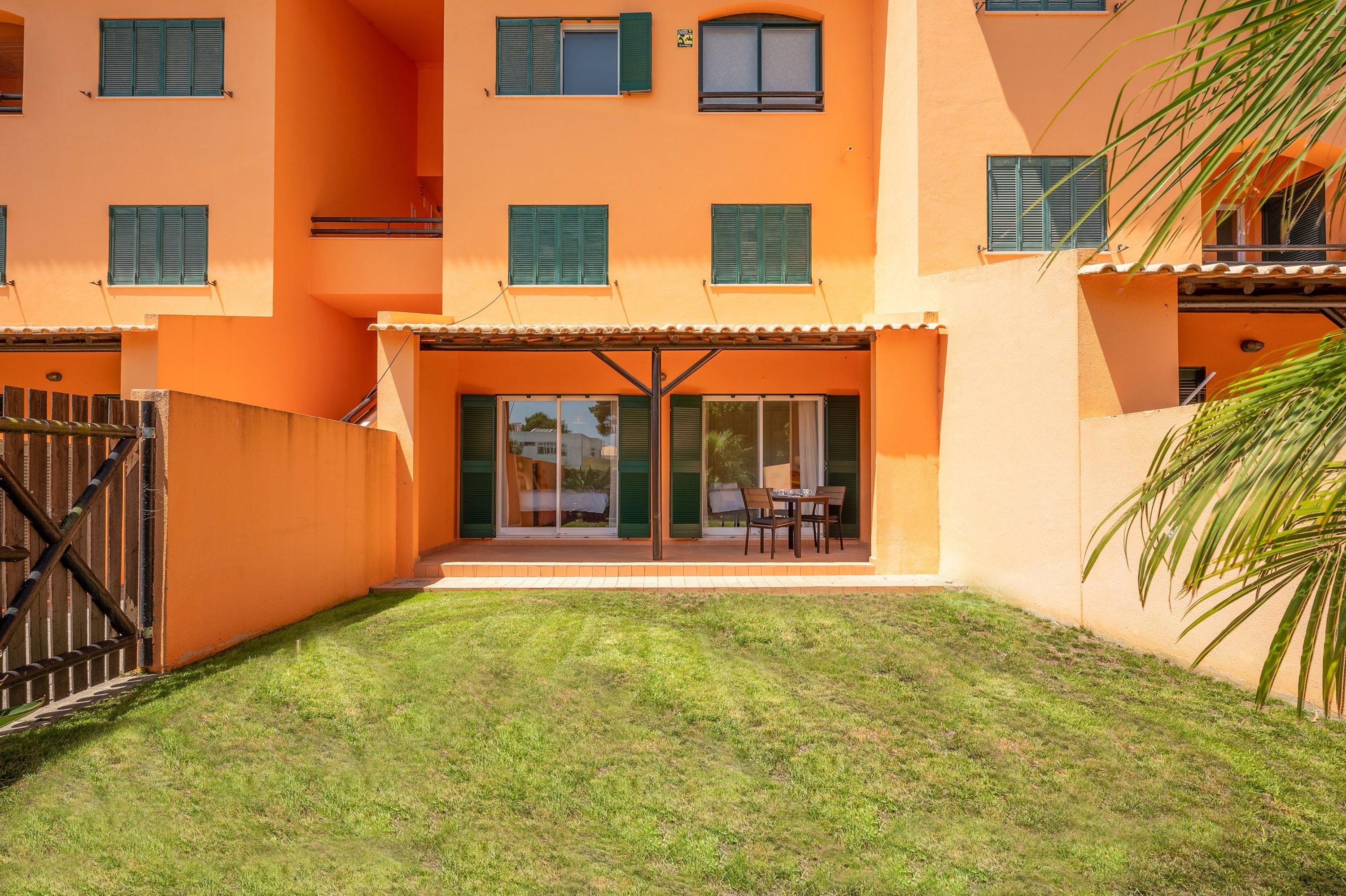 A building with a flat roof, multiple windows with shutters, and a covered patio area with outdoor seating.