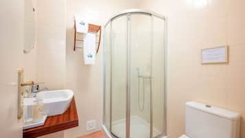 Un baño con ducha de vidrio, lavabo con encimera de madera y retrete blanco.