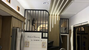 A modern kitchen with a built-in refrigerator, wooden cabinets, and a staircase with a black railing.