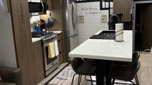 A modern kitchen with a central island, stainless steel appliances, and a dining area with black chairs.