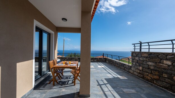 A balcony with a table and chairs, overlooking a scenic view of the sea. - Casa da Fazenda by LovelyStay (Gaula)