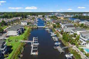 A marina with docks, boats, and residential buildings along the water. - Carolina Yacht Landing 15-A (Little River)