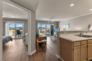 Eine moderne Küche mit einer großen Kochinsel, ein Essbereich mit Aussicht und ein Schlafzimmer mit Balkon.