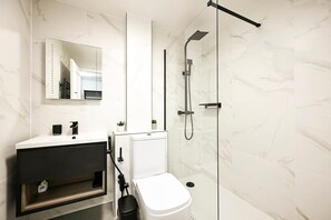 A modern bathroom with a white sink, mirror, and glass-enclosed shower. - Maida Vale Escape (Greater London)