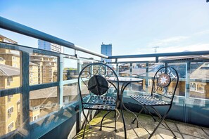 A balcony with two metal chairs and a table, overlooking a cityscape with buildings. - Maida Vale Escape (Greater London)