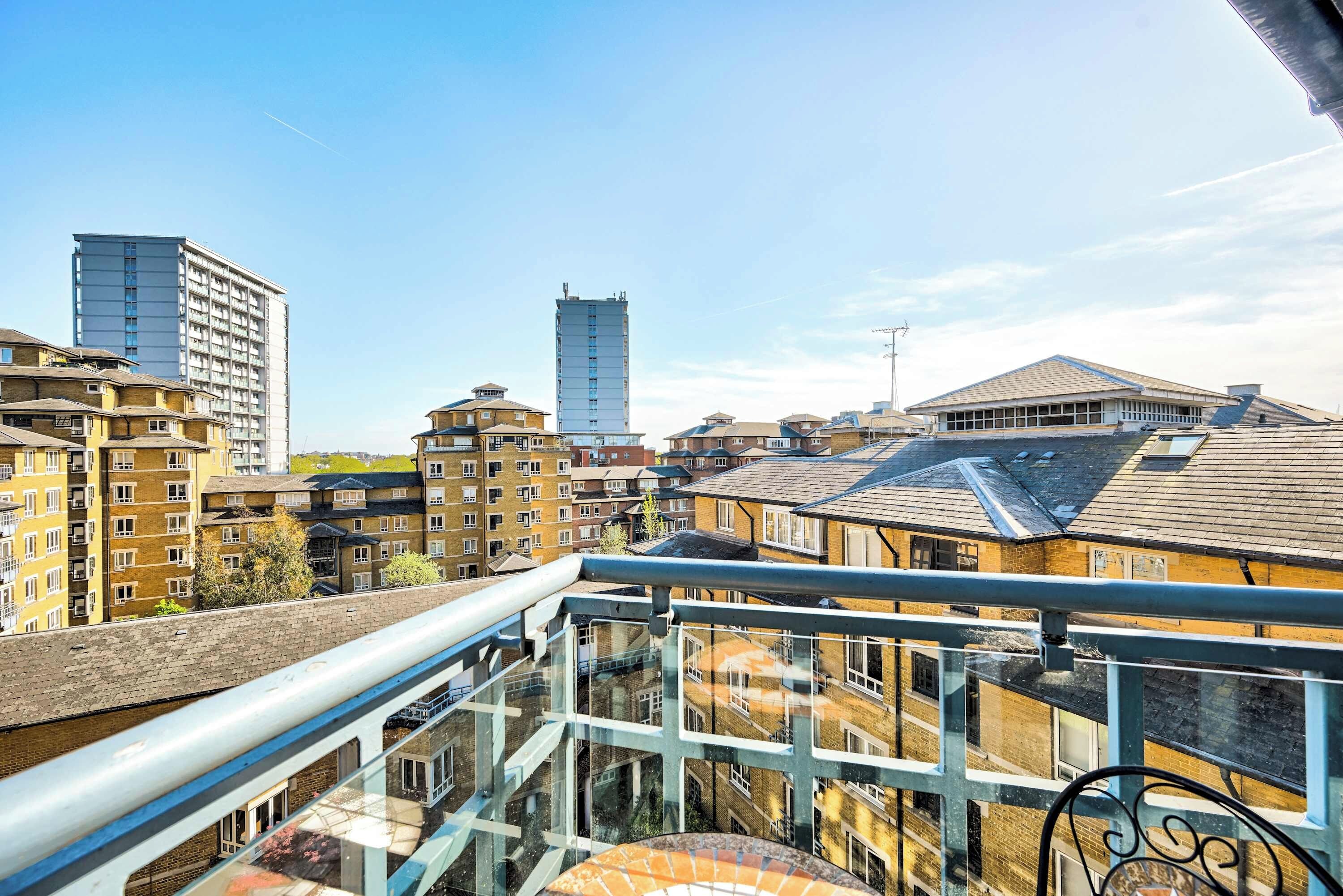 A high-rise building with multiple balconies, a glass walkway, and a clear sky.
