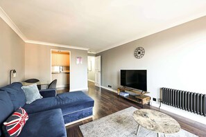 A modern living room with a blue sofa, a coffee table, a TV, and a radiator. - Maida Vale Escape (Greater London)