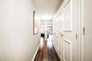 A hallway with white walls, wooden flooring, and white doors. - Maida Vale Escape (Greater London)